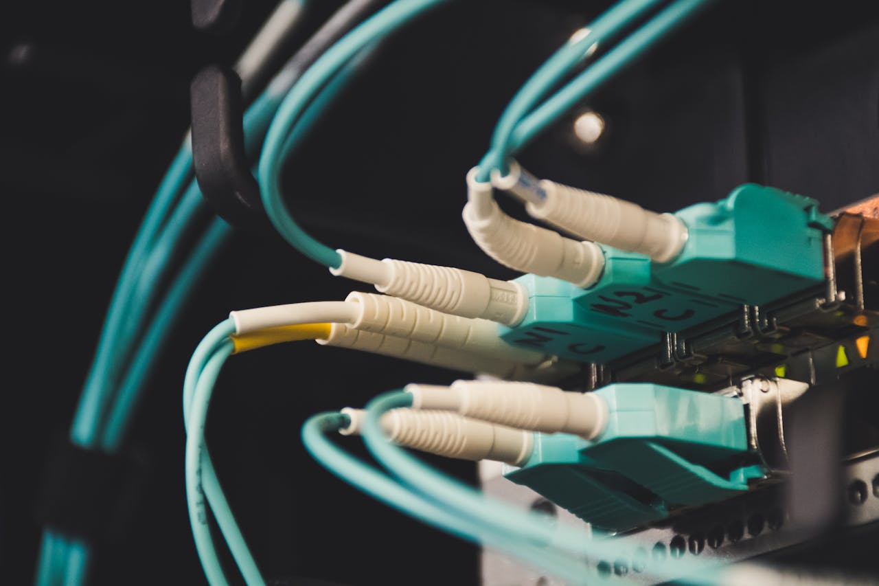 why-choose-us Detailed view of fiber optic cables and ports in a server room, showcasing connectivity.