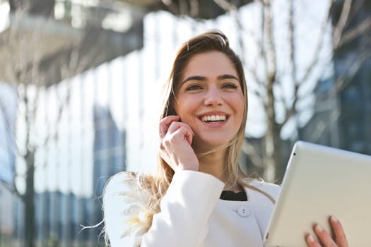 Contact Confident businesswoman using her tablet and phone, smiling outdoors in sunlight.